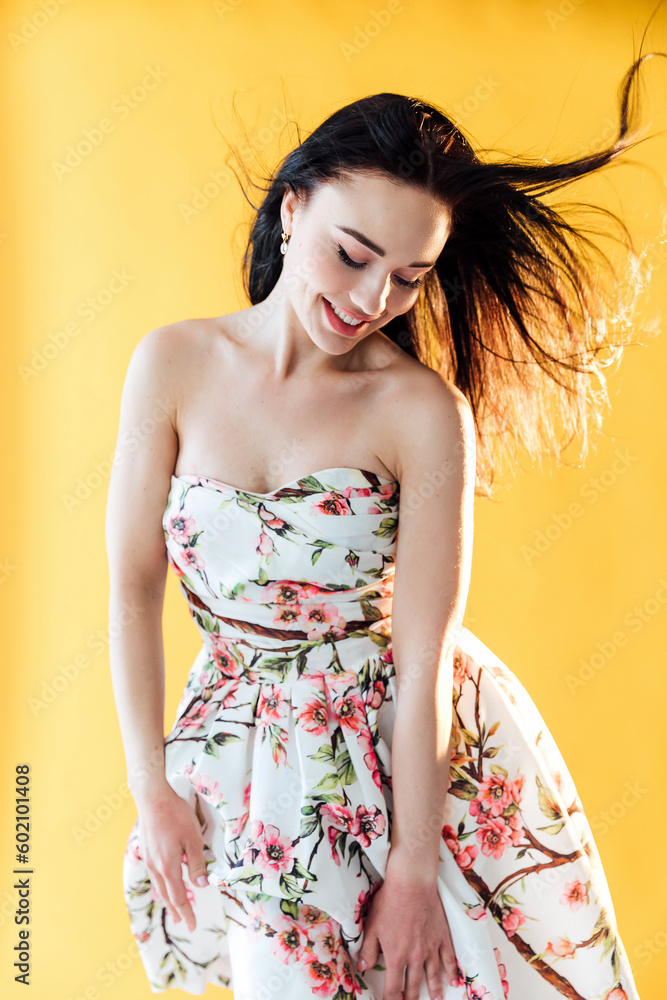 Fototapeta premium beautiful woman in a floral dress posing in a bright room