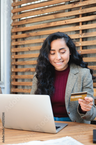  Young, Smiling Brunette Latin Woman at a Patio Cafe with Laptop, using a credit card to buying online