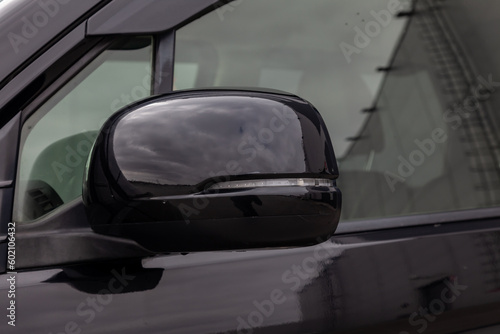 Close-up of the side left mirror with led turn signal and window of the car body black SUV on the street parking after washing and detailing in auto service industry. Road safety while driving © Aleksandr Kondratov
