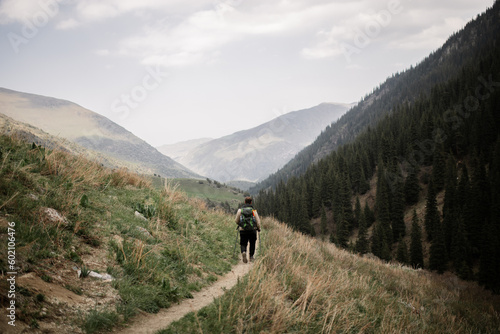 Man Trekking through Green Meadows and Mountains