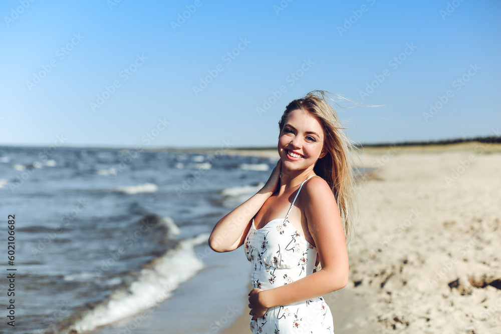 Happy blonde woman in free happiness bliss on ocean beach standing straight and posing