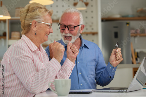 Wallpaper Mural Excited and happy elderly couple shopping online from home using computer, smartphone and credit card. Modern technologies and retirement concept. Torontodigital.ca