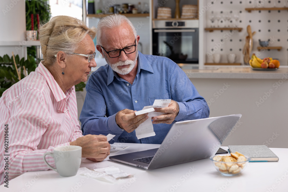 Worried senior couple checking their bills and receipts sitting at home with laptop. Frustrated elderly husband and wife having problems with finances or struggling with paying the bills online Worried senior couple checking their bills and receipts sitting at home with laptop. Frustrated elderly husband and wife having problems with finances or struggling with paying the bills online