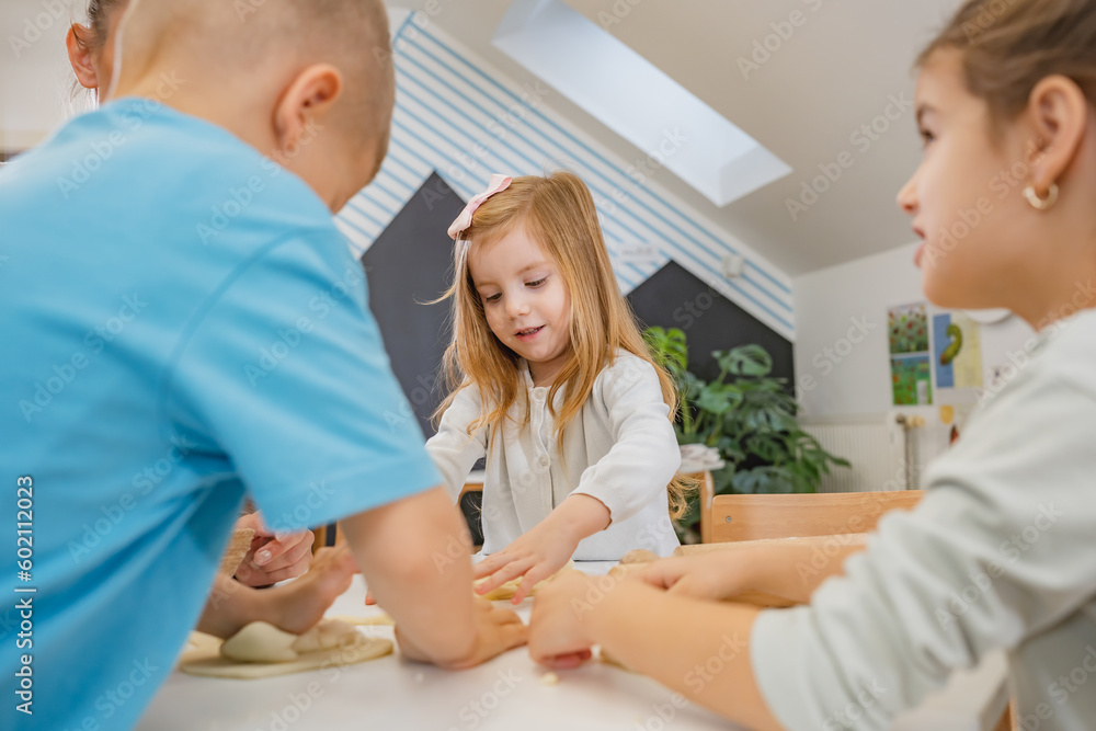 Fototapeta premium Happy cheerful children playing with a play dough in a kindergarten