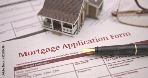 Mortgage loan or home equity loan, financial concept : Model residential house, a pen on mortgage application, depicting home loan or borrowing money to purchase a new home for first time homebuyer.