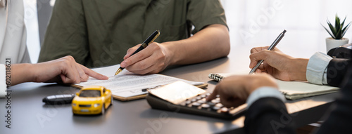 Car dealer calculate interest rate and costs of car loan with calculator, explaining details to customer on term and agreement in dealership office, offering financial and insurance service. Prodigy
