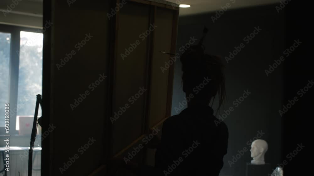 A red-haired girl artist carries to install a canvas on an easel in a loft studio. Creating a masterpiece in the workshop. A red-haired girl artist carries to install a canvas on an easel in a loft studio. Creating a masterpiece in the workshop.