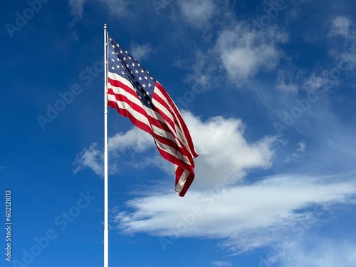 American flag blowing in the wind with a partly cloudy blue sky, USA photo