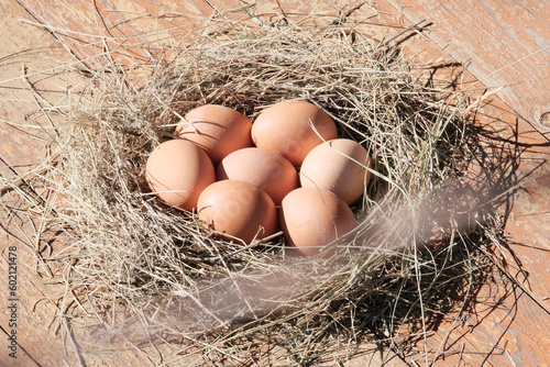 Brown eggs in a light wooden basket, nest. Farm food product. Beautiful sunny background with eggs.