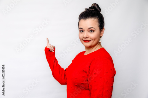 Brunette Young Woman Pointing at Blank space with confident, friendly, poised expression wearing a festive red sweater