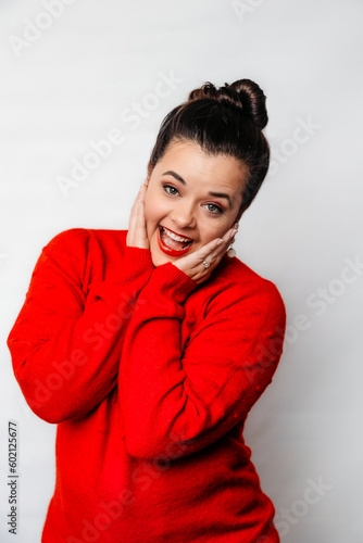 Brown haired woman with a thrilled expression in a festive red sweater