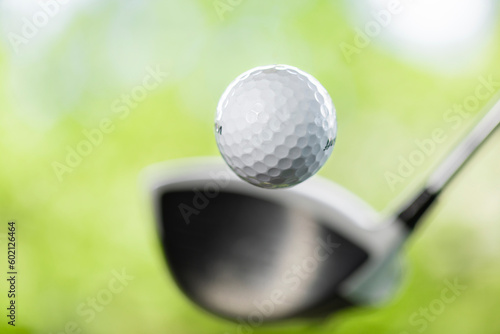 Golf ball swing action on golfer's first stroke with drivers. Close up of golf ball coming out after golf shot. Close up view of ball after crive hit on tee on golf course isolated blur background