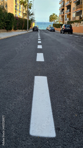 Level asphalted road with a dividing white stripes. The texture of the tarmac, top view. High quality photo