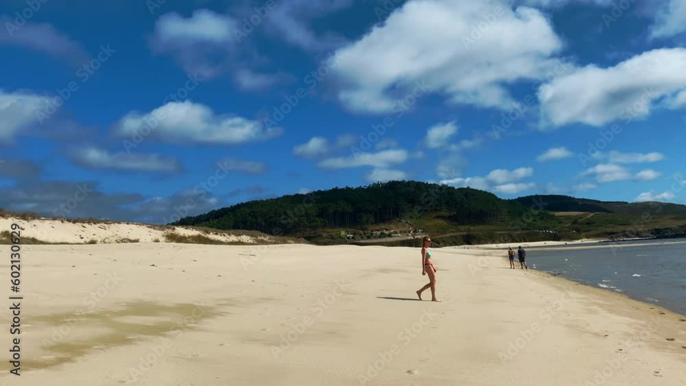 Young woman walking along a wonderful beach on a sunny and relaxing day