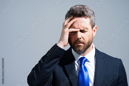 Stressed business man in suit having headache. Tired businessman is working overtime and has headache. Overworked man suffers from headache. Migraine from overwork, deadline, difficult at work.