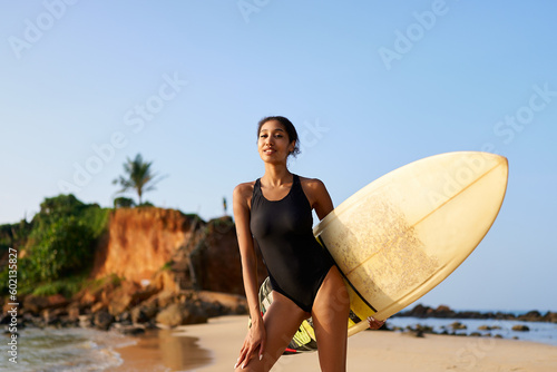 Canvas Print African american woman standing with surfboard on ocean beach