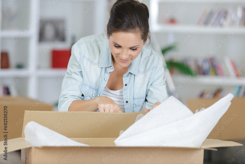 young woman packing a box - obrazy, fototapety, plakaty 