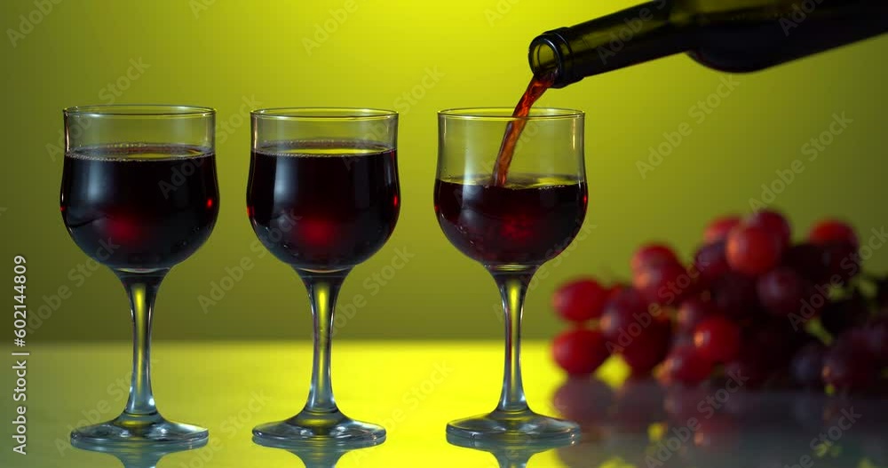 Wine. Pouring red wine into glass from the bottle on the black