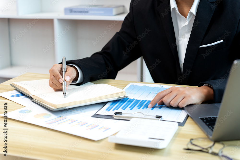 businesswoman Sitting at desk using smartphone and laptop with data from graph businesswoman Sitting at desk using smartphone and laptop with data from graph