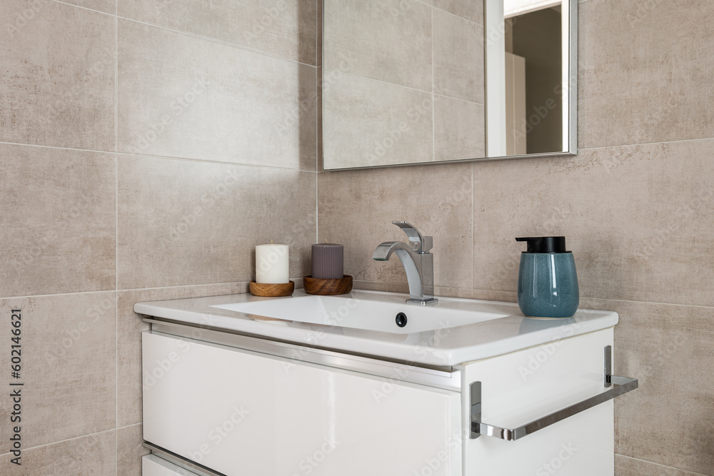Comfortable bathroom with sink and mirror with beige tiles and natural lighting. The concept of a bathroom in hotel or apartment after a purchase with a mortgage Comfortable bathroom with sink and mirror with beige tiles and natural lighting. The concept of a bathroom in hotel or apartment after a purchase with a mortgage