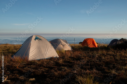 Três barracas de camping ao amanhecer com céu azul photo