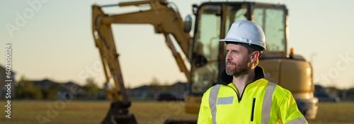 Portrait of worker man small business owner. Construction worker with hardhat helmet on construction site. Construction engineer worker in builder uniform with excavation truck digging. Worker