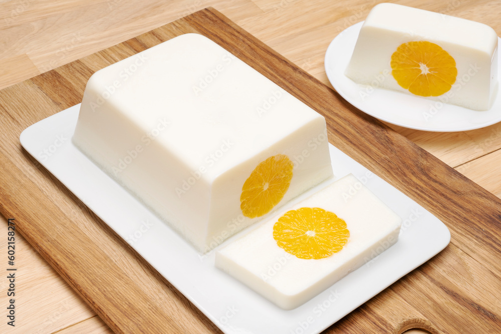 Milk orange jelly square shape on a white platter on a wooden table. Milk orange jelly square shape on a white platter on a wooden table.