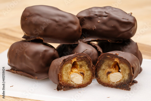 Natural date dessert with peanuts in chocolate, on a wooden table. 