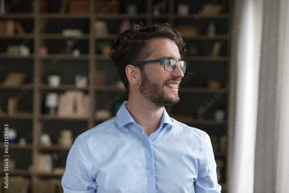Positive dreamy handsome young business man in trendy eyeglasses, looking at window away, thinking, dreaming, smiling, laughing. Handsome young male model with curly hair candid portrait Positive dreamy handsome young business man in trendy eyeglasses, looking at window away, thinking, dreaming, smiling, laughing. Handsome young male model with curly hair candid portrait