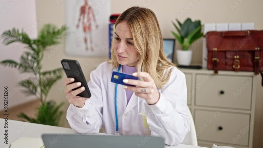 Young beautiful hispanic woman doctor using smartphone and credit card working at clinic Young beautiful hispanic woman doctor using smartphone and credit card working at clinic