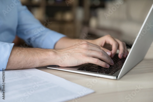 Caucasian young businessman working at laptop, typing on keyboard. Male employees hands close up. Business professional man in casual working at table, using online app, chatting. Cropped shot