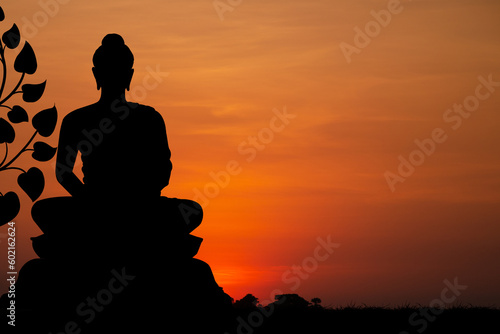Silhouette with buddha statue sitting on sunset background.
