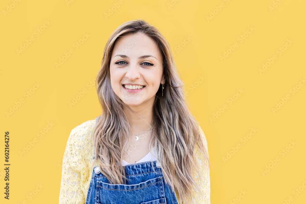 Fototapeta premium Cheerful portrait of young blonde girl looking at camera smiling over yellow background