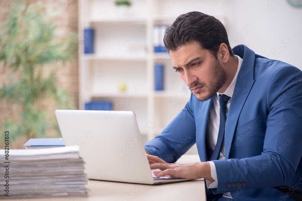 Young male employee and too much work in the office Young male employee and too much work in the office