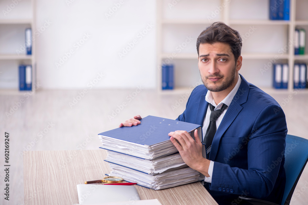 Young male employee and too much work in the office Young male employee and too much work in the office