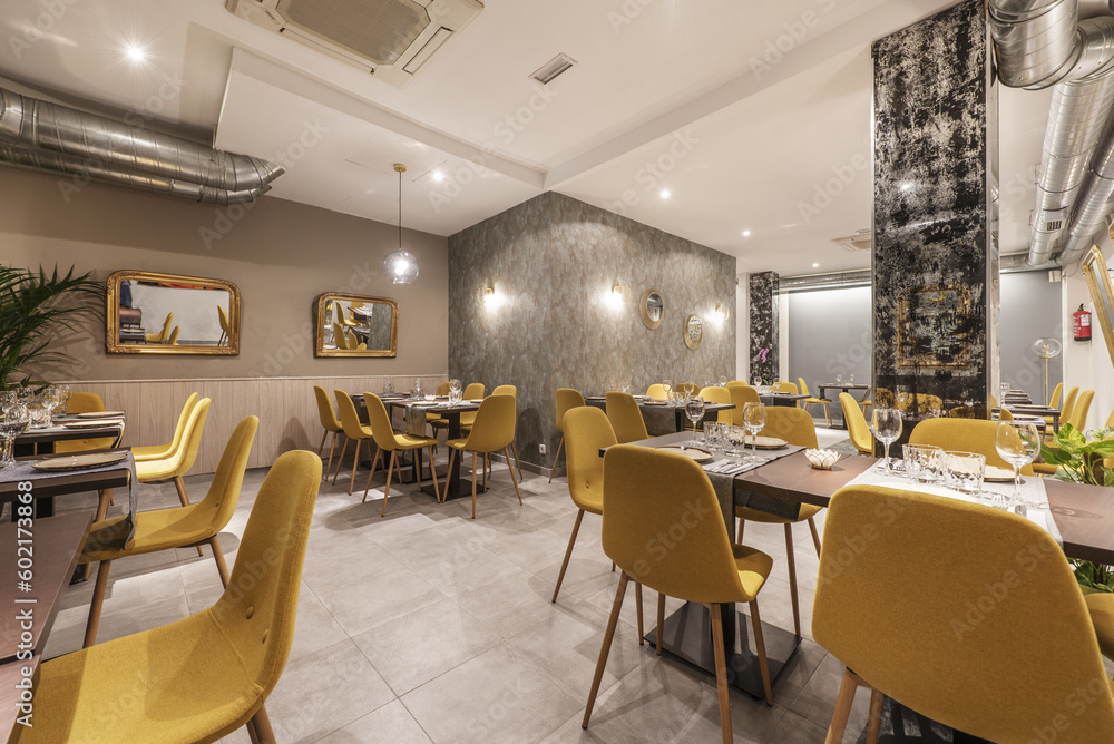 dining room of a restaurant with wooden tables, yellow upholstered chairs