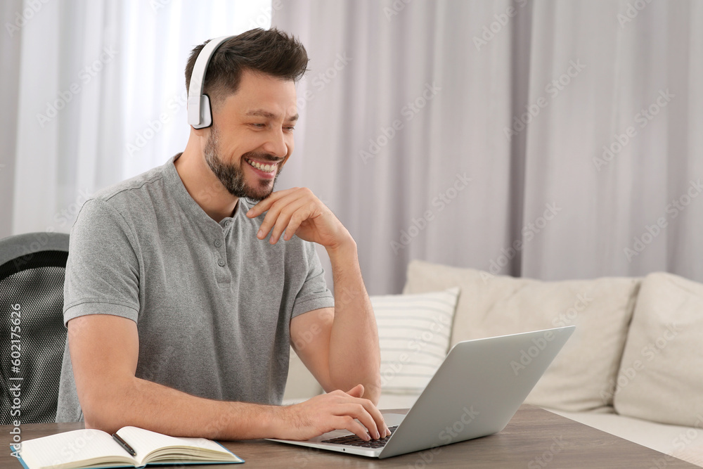 Man in headphones studying on laptop at home. Online translation course Man in headphones studying on laptop at home. Online translation course