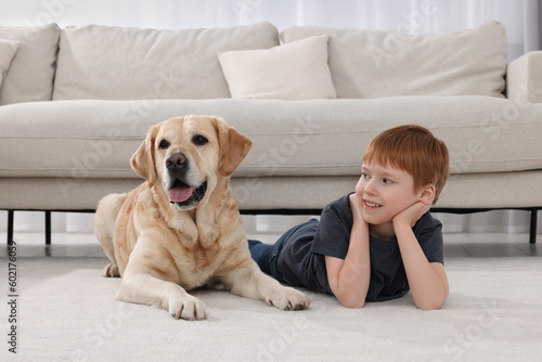 Cute child with his Labrador Retriever on floor at home. Adorable pet