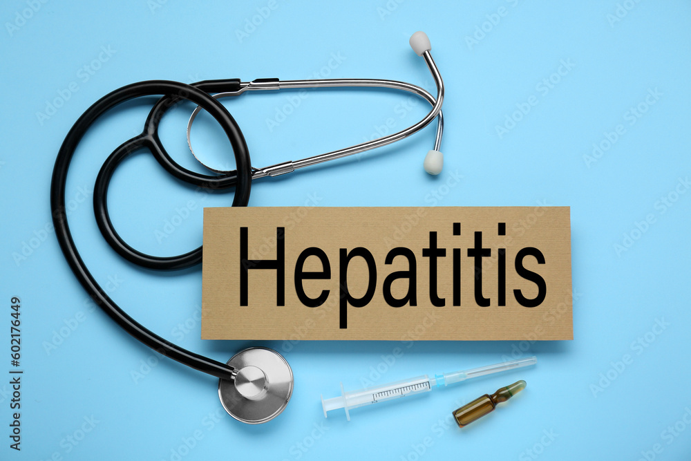 Cardboard with word Hepatitis, stethoscope, syringe and vial on light blue background, flat lay Cardboard with word Hepatitis, stethoscope, syringe and vial on light blue background, flat lay