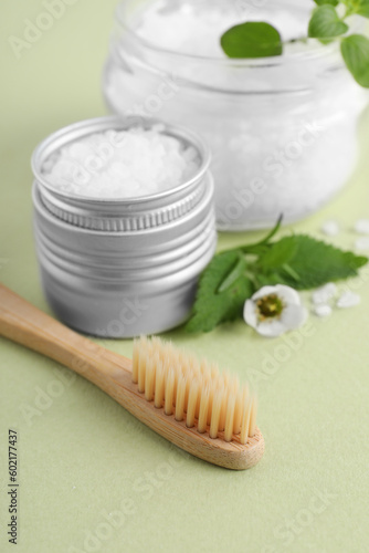 Toothbrush, dental products and herbs on light olive background, closeup