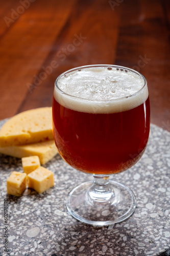 Glass of Belgian light blond beer made in abbey and tasty belgian cheese