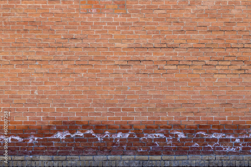 Full frame texture background of an antique exterior red brick wall with salt deposits from moisture and efflorescence