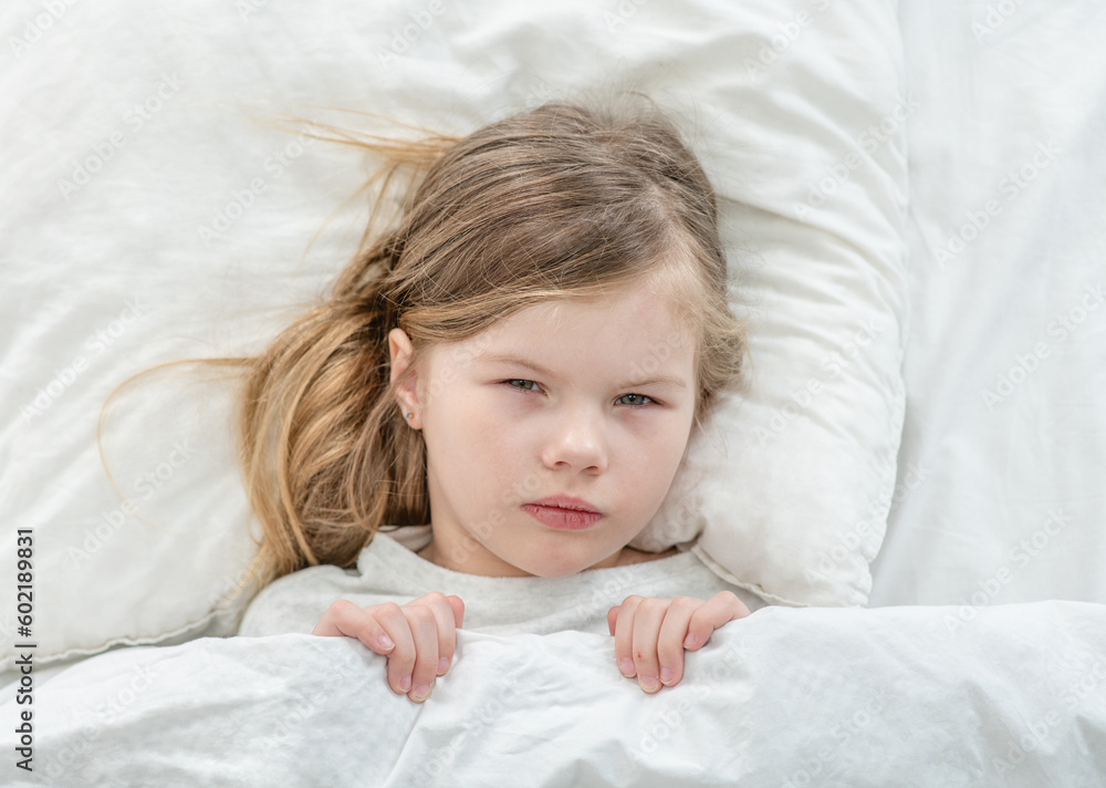 Sick little girl lying on the bed at home. Top down view Sick little girl lying on the bed at home. Top down view