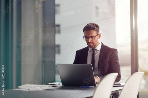 Business man, corporate office and laptop in online management, career planning and company software. Serious, focus and professional person or worker in conference room typing on computer or website © GR/peopleimages.com