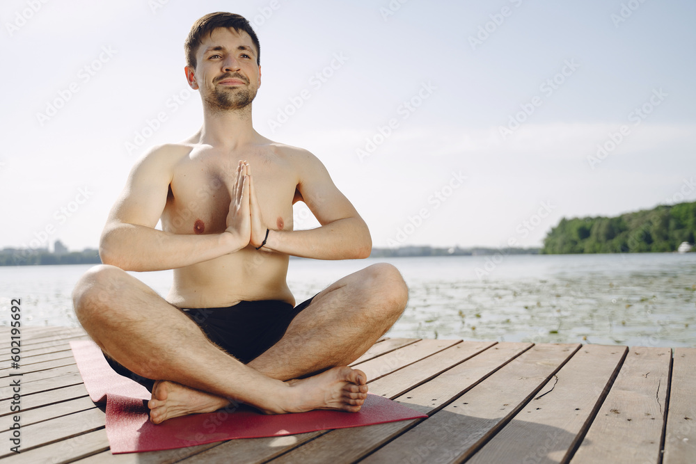Young man is practicing yoga at river