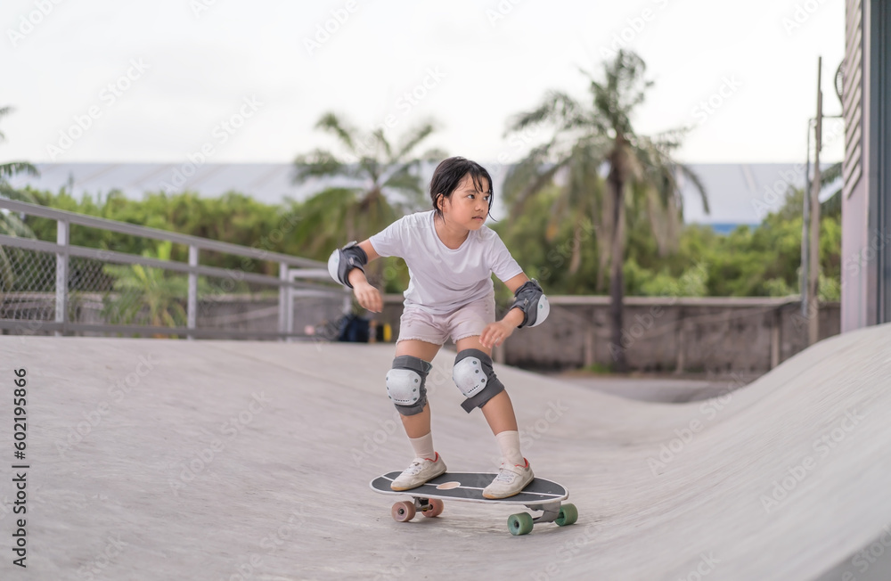 asian child skater or kid girl playing skateboard or ride surf skate up to wave ramp or wave bank to fun bottom turn surfskate in skate park by extreme sport surfing to wears knee pads for body safety