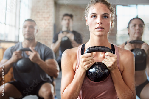 Fitness, exercise and woman with kettlebell in a gym for a strength training challenge. Sports, energy and female athlete doing a workout with weights with her friends or community in wellness center
