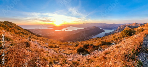 Panoramic photo of the Bay of Kotor taken from mountain at sunset with yellow foreground and blue sky © Howard Darby