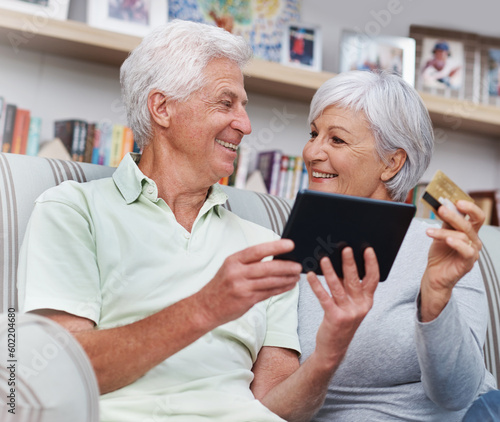 Senior couple, tablet and credit card for online shopping on living room sofa together at home. Happy elderly man and woman smiling on technology for ecommerce, banking app or payment on lounge couch