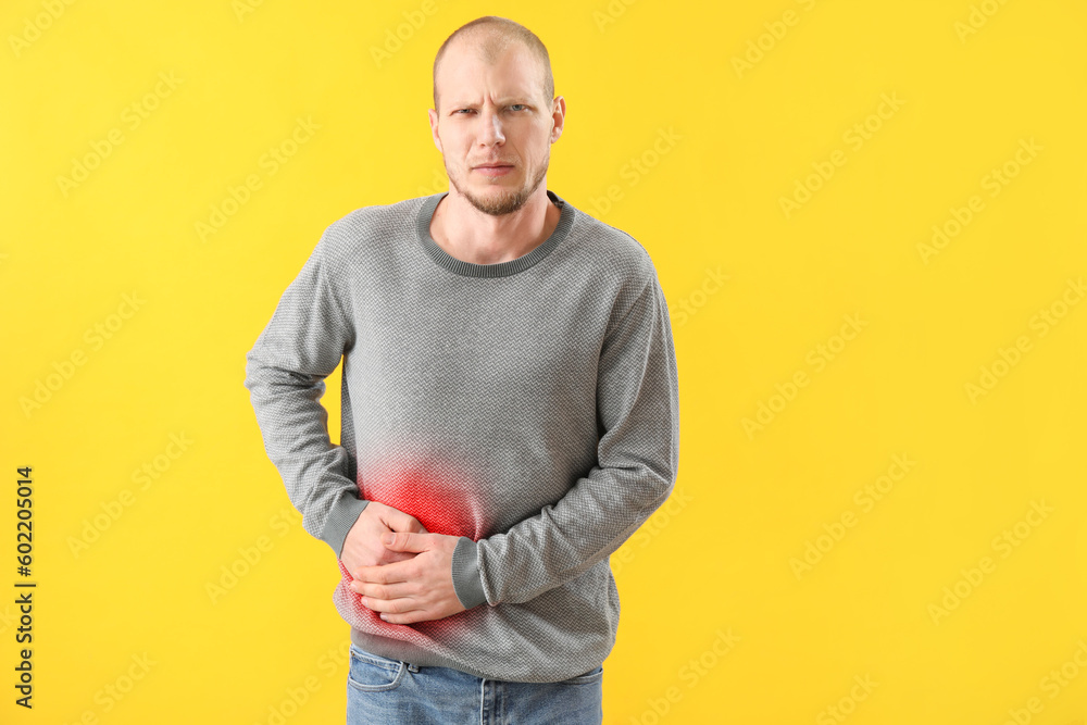 Young man suffering from appendicitis on yellow background Young man suffering from appendicitis on yellow background